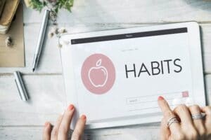 tablet on table with word Habits dislpayed as woman searches for good habits