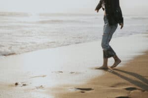 woman walking barefoot on beach get organized enjoy life