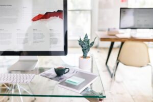 computer and office supplies sitting on glass desk