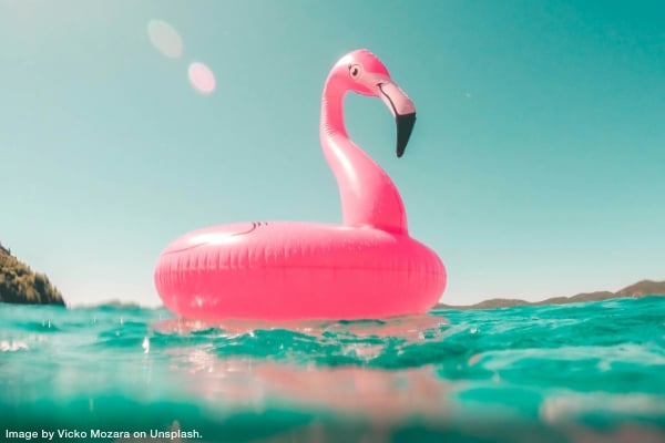 pink flamingo inflatable water toy floating in the water at the beach representing how vacations boost your productivity