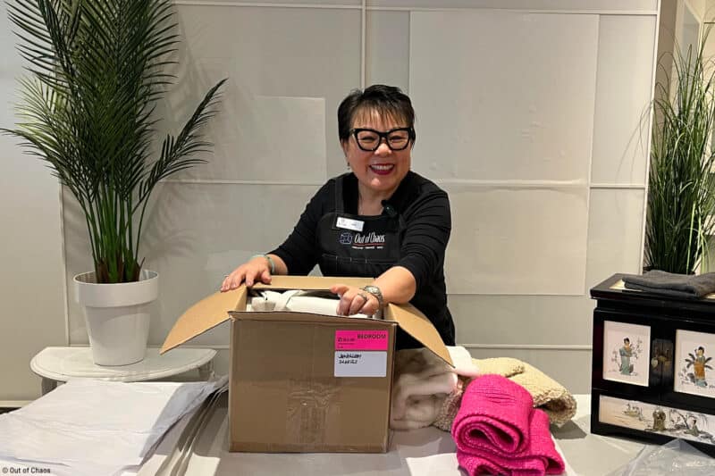 Linda Chu, founder of Out of Chaos packing moving box representing reasons to hire a move manager