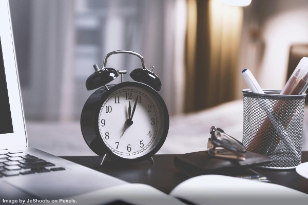 clock beside computer on desk representing giving your productivity a big HIIT