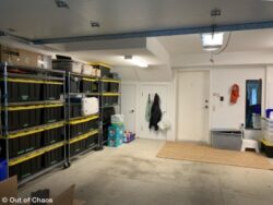 looking at the left hand side of the organized garage using black bins with yellow lids on stainless steel shelving pushed up to the wall with no clutter on the floor