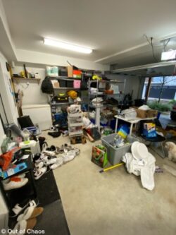 looking at the right hand side of an untidy garage with clutter on the floor and a freezer and shelving against one wall and shelves in the middle of the floor