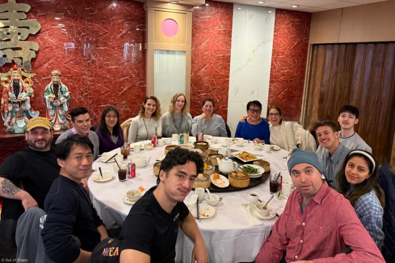 Out of Chaos team members sitting around a table enjoying dim sum at their modern office holiday party