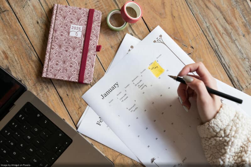 person writing resolutions on paper calendar to make lasting changes