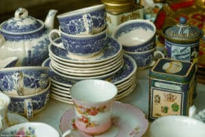 vintage tea set and other fine china on display at a flea market representing what millennials do when they inherit tons of stuff