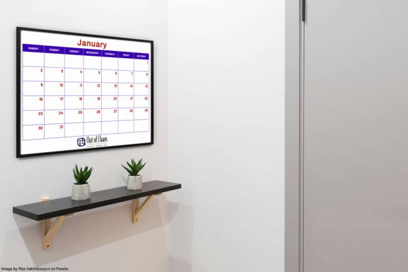 family calendar on wall above a shelf showing a one-month view